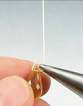 Pliers bending wire around glass bead